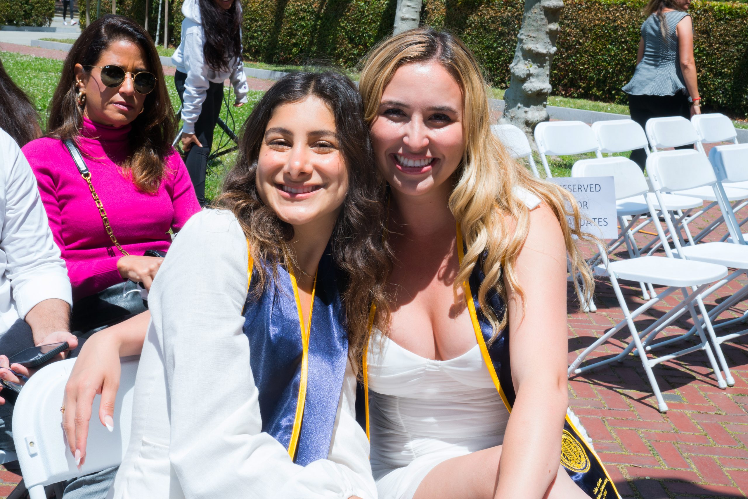  Friends and colleagues, Careena El-Khatib (left) and Celine Wheritt (right), smile for a picture in their seats as they wait for the ceremony to begin. 